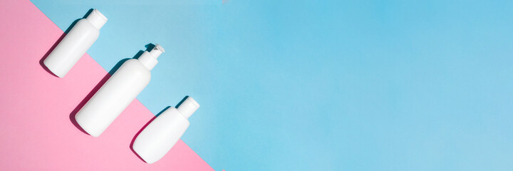 Banner with white cosmetic bottles mock up for branding on pink and blue background. Tubes, dispensers and jars. Branding identity concept. Flat lay