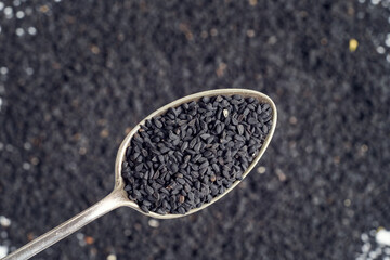Black cumin seeds on a spoon, top view