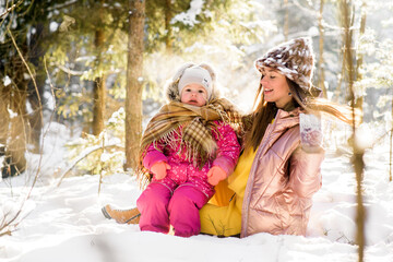Obraz premium mother and daughter wrapped in a scarf in a snowy winter forest.
