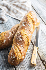 Two crispy fresh baguettes on wooden table.