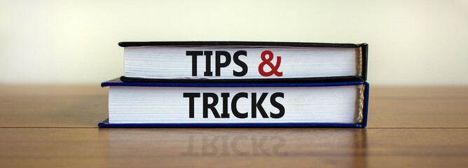 Tips and tricks symbol. Books with words 'Tips and tricks'. Beautiful wooden table, white...