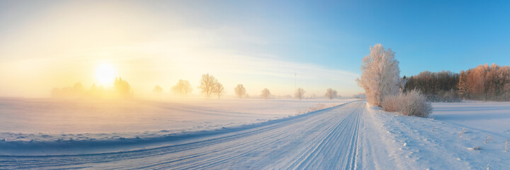 Panoramic view of snowy countryside with road at sunrise