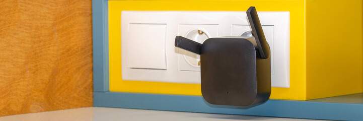 WiFi repeater in an electrical outlet on a yellow wall. An easy way to extend your wireless network...