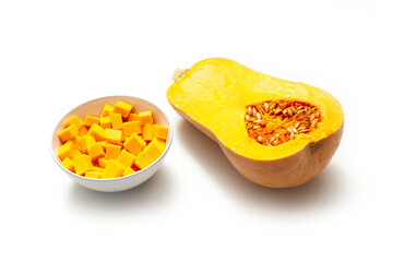 cut pumpkin half and bowl of pumpkin cubes on white background