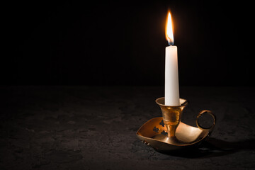 Burning candle  in vintage candlestick on black background
