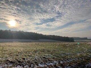 snow melting on a wide field on a sunny winters day with some clouds