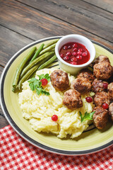 Swedish meatballs with mashed potatoes and green beans on wooden background