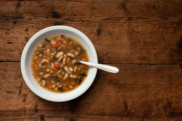 typical dish of Tuscan minestrone on wooden table. view from above