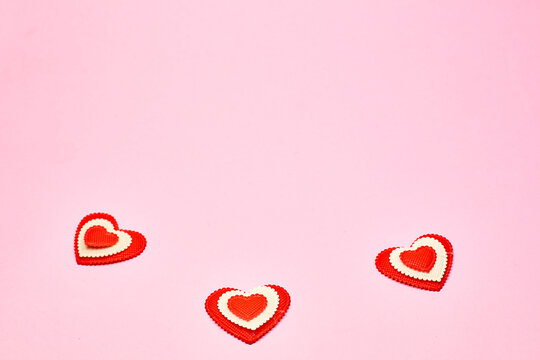 small red hearts on a soft pink colored background, copy space. Valentine's Day concept for design