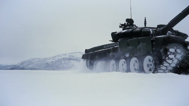Snow-covered shooting range field on the background of the mountain. Tracked tank rides on the field