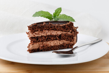 Piece of chocolate cake with mint on white plate
