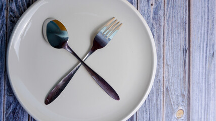 Set of empty ceramic dish (plate), spoons and forks isolated on wooden background. Flat lay, Top view. Minimal style.