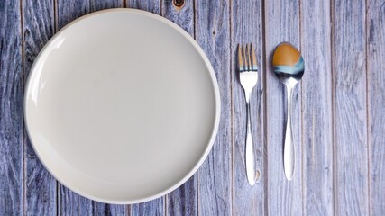 Set of empty ceramic dish (plate), spoons and forks isolated on wooden background. Flat lay, Top view. Minimal style.
