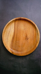 wooden empty plate on a dark stone background, a blank for design.