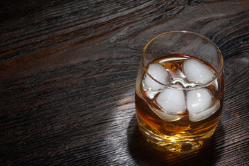 Glass of whiskey with white ice on a wooden table