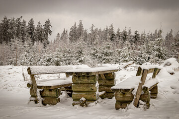 verschneite Bank im Winterwald