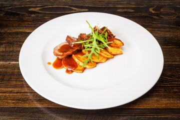 Juicy piece of grilled meat with fried potatoes and arugula