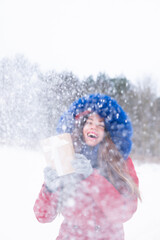 Young woman in red coat enjoying snowfall 