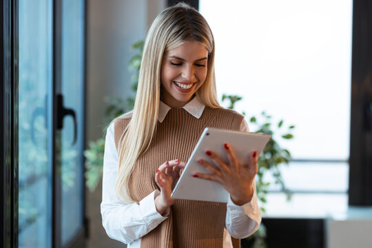 Pretty young businesswoman working with digital tablet standing in the office.