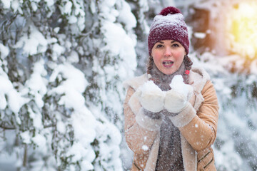Happy woman on the background of the forest, snow falls on the girl, the female smiles in winter. Copy Space