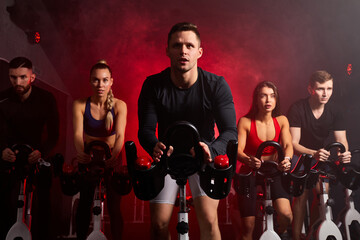 sportsman diligently riding an exercise bike in gym, the guy is exercising on a stationary bike