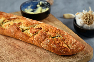 Baguette bread baked and stuffed with herb butter cut into pieces on wooden tray
