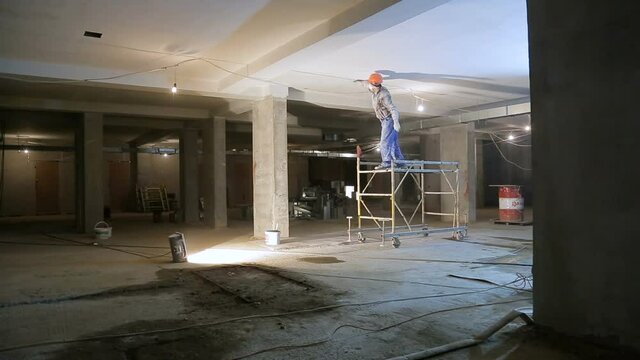 Large empty building where repairs are made. Worker in a helmet and mask. Russia. 09.01.2018