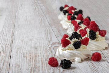 Pavlova cake. The cakes are on a wooden table. Sweet Dessert. A treat for guests. Dessert for the holiday. Cake decorated with berries.