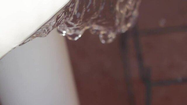 Drops of water falling from a table. Water fall in slow motion from white table