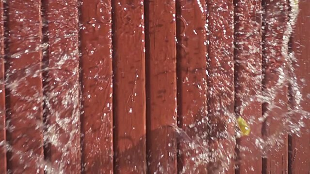 Water balloon exploding on wooden boards. Water explosion in slow motion