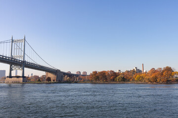 Fototapeta na wymiar The Triborough Bridge over the East River with the Shore of Randalls and Wards Islands during Autumn with Colorful Trees in New York City