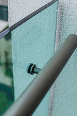 Metal fastening of handrails to balcony glass partition.