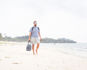 Cheerful adult man with bag having fun on the tropical beach