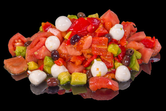 Tasty salad with avocado, tomatoes, cucumber, fresh cheese, and olives with reflection