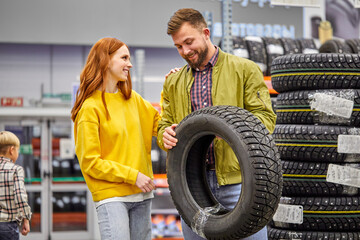 Fototapeta na wymiar couple choose tire for their first car in the store, discuss, have talk in the shop, wearing casual clothes