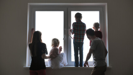 Fototapeta premium Silhouette of a large family on the background of a window in a new apartment.