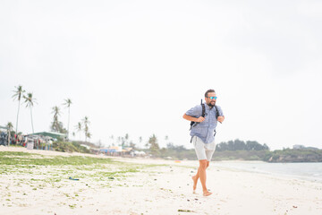 Cheerful adult man with bag having fun on the tropical beach