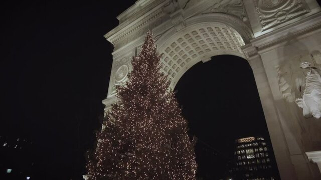 Washington Square Park Arch in downtown Manhattan by Washington Square Park during Christmas with a large illuminated beautiful Christmas tree. Filmed at night.