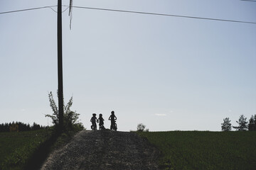 Naklejka na ściany i meble Children bicycling on a gravel road in the fields. 