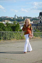 Fashionista in white flare pants and a beautiful retro bag on a walk