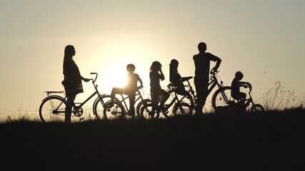 A friendly large family with bicycles at sunset.