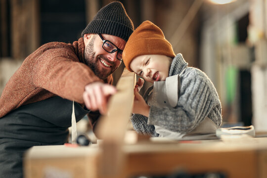 Happy kid helping father in carpentry studio