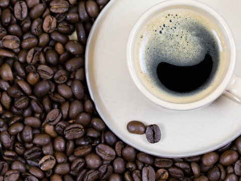 a cup of coffee on the background of coffee beans. View from above © OlgaFet