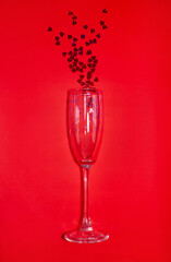 Red hearts flow out of a champagne glass. Red background, top view. The concept of Valentine's day.