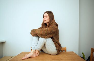  woman in casual domestic clothes sitting with crossed arms.
