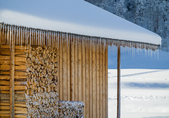 Fototapeta premium Wooden huts covered in snow and perfectly lined up icicles