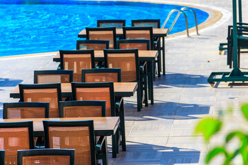Fototapeta premium Tables and chairs of outdoor restaurant near swimming pool at luxury hotel