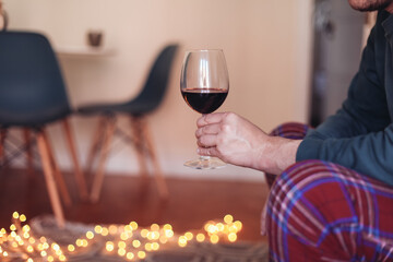 Man holding a glass of red wine, sitting at home