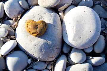 Stone heart among river or sea pebble stones, Valentine's Day, perfect love