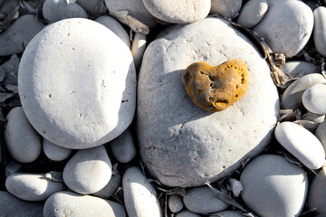 Yellow stone heart among river or sea pebble stones, Valentine's Day, perfect love. Romantic photo, I love you